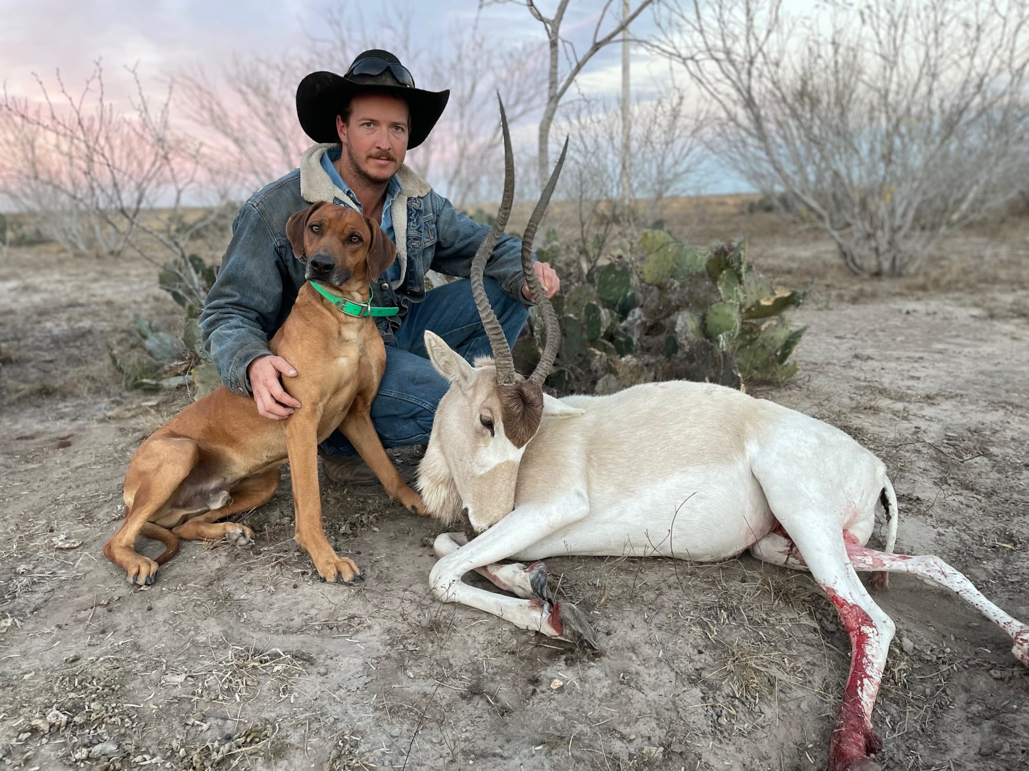 man and dog posing with hunted wildlife