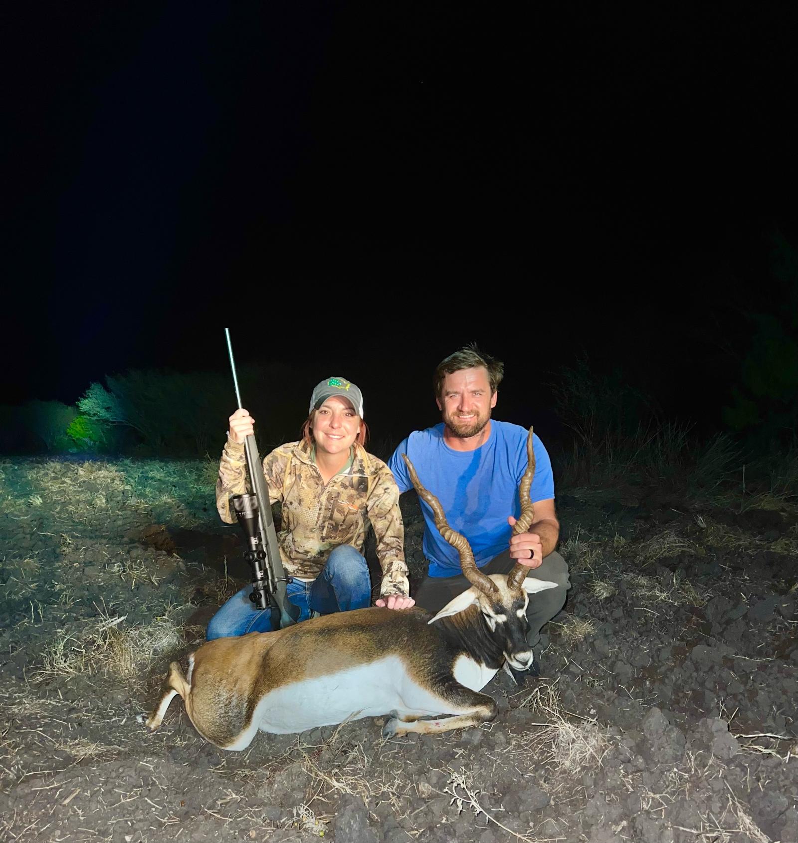 man and woman posing with hunted exotic animal