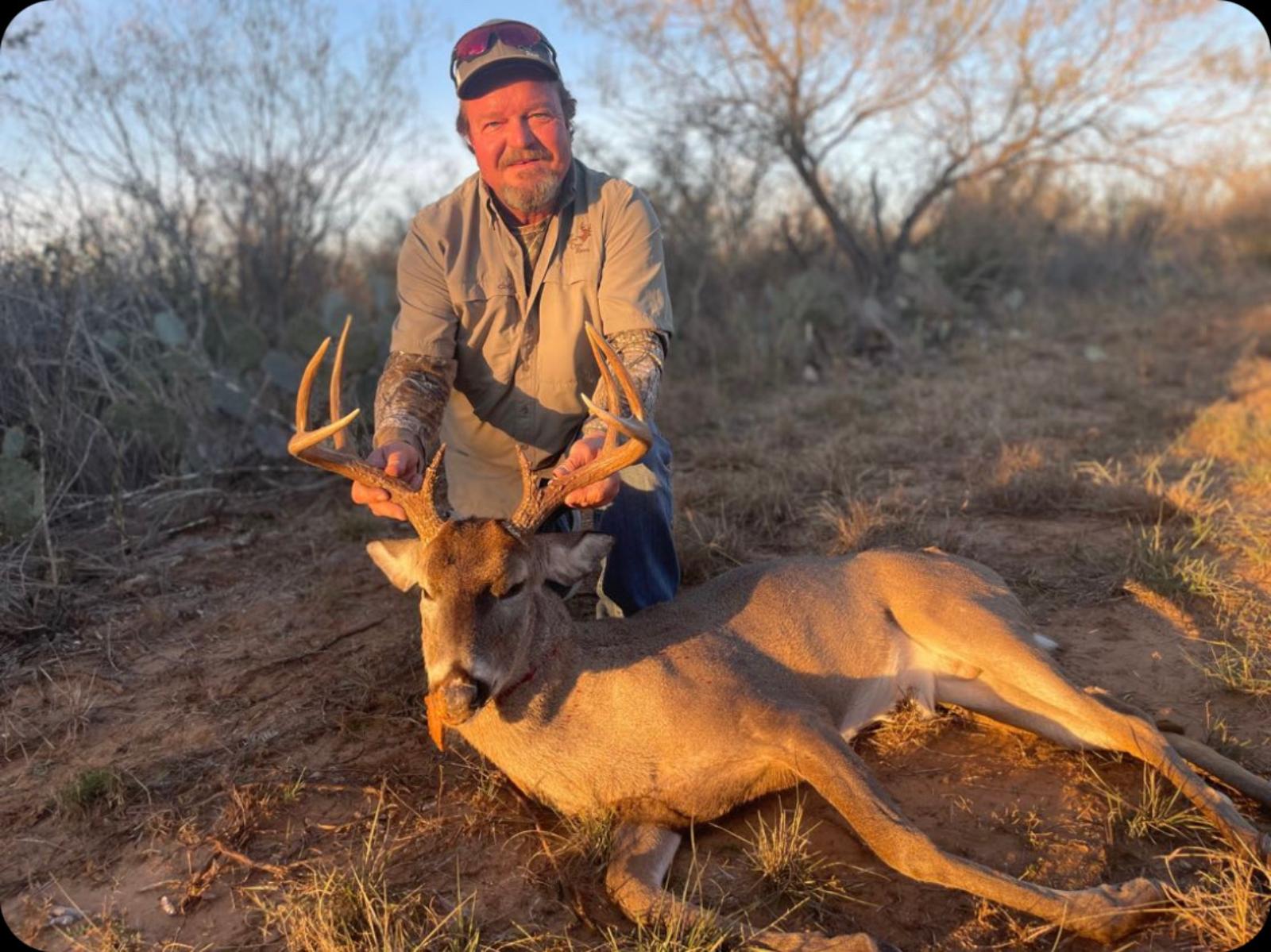 man posing with hunted buck