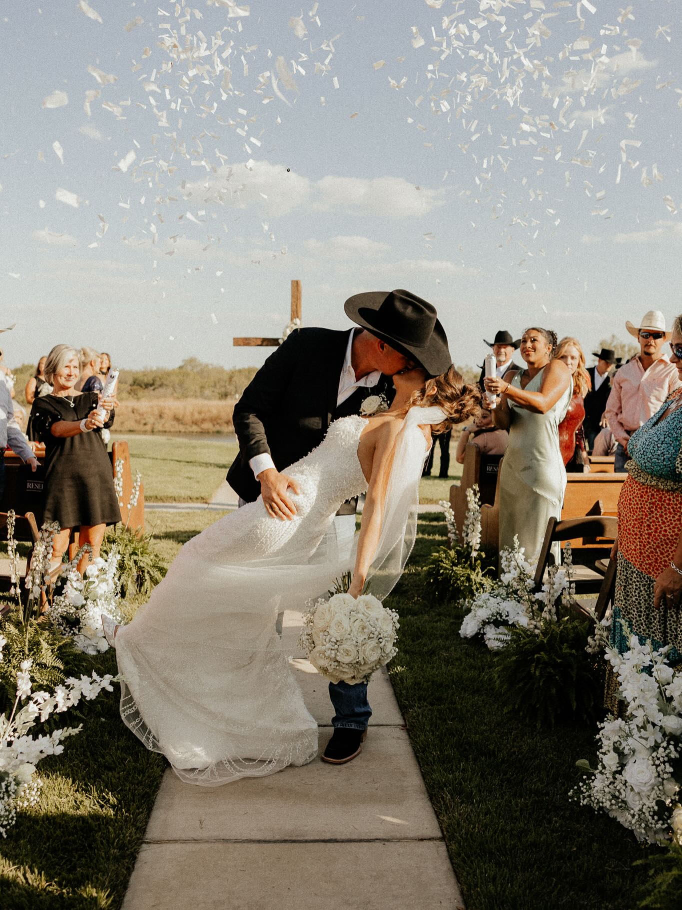 a bride and groom kiss as they walk down the aisle with crowd cheering